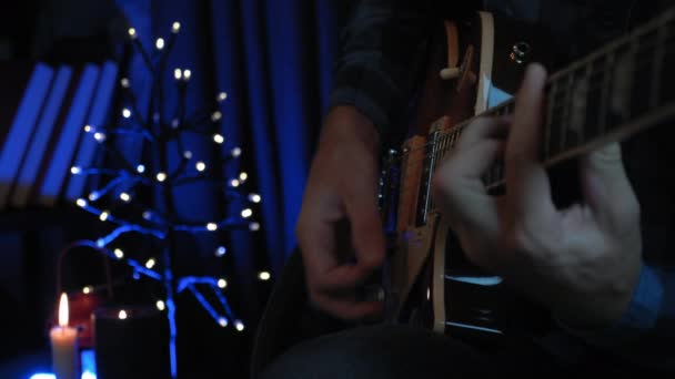 Profesionální hudebník hraje na elektrickou kytaru, hraje píseň v moderním zkušebním studiu se světly. Muž kytarista nacvičuje sólovou kytarovou část sedící na gauči v tmavém obývacím pokoji — Stock video