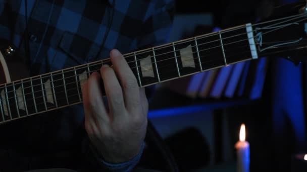 Muzikant speelt akkoorden op akoestische gitaar in donkere opnamestudio met licht op de achtergrond. Mannelijke solo gitarist speelt lyrische muziek op gitaar — Stockvideo