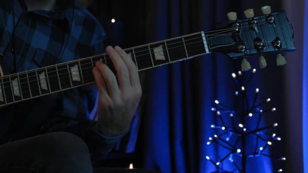 A zenész élő előadáson gitározik. A férfi ujjak gitárhúrokon játszanak a stúdióban. Férfi kéz gitározik a sötét szobában. A gitáros otthon próbál gitárral. — Stock videók