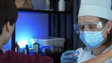 Güvenlik eldivenleri ve koruyucu tıbbi maske takan tıp hemşiresi sağlık kliniğinde aşı yapıyor. Kadın doktor aşıyı koymak için şırınga ve şırınga kullanıyor. Tıp konsepti