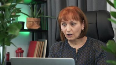 Kadın finans piyasasında elde ettiği iyi mali sonuçlarla heyecanlanıyor, el çırpıyor ve işindeki başarıyı kutluyor. Mutlu iş kadını laptoptan gelen iyi haberlerin keyfini çıkarıyor.