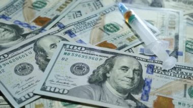 Kullanılmış şırınga Amerikan doları banknotlarının üzerinde yatıyor. Banknotlarda uyuşturucu olan şırınga. Uyuşturucu bağımlılığı ve sağlık hizmetleri kavramı