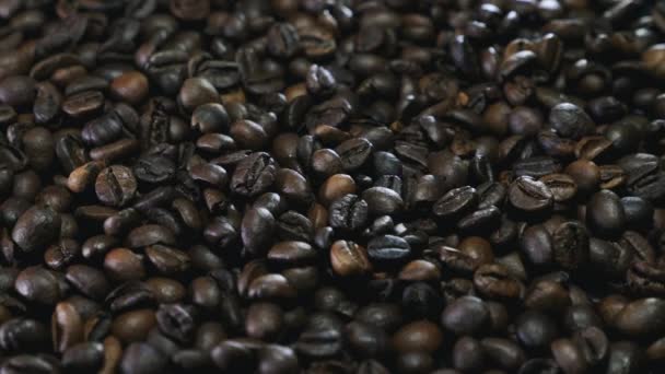 Arabica memanggang biji kopi yang berputar di atas meja, tutup. Biji-bijian kopi berada di latar belakang hitam — Stok Video