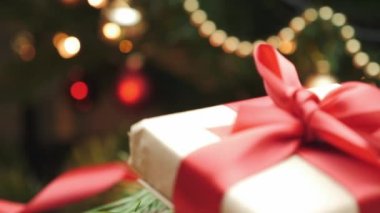 Ağacın altında kırmızı kurdele ile el işi kağıdına sarılmış. Noel ve yeni yıl süslemeleri. Dekorlu tatil hediyesi kutusu