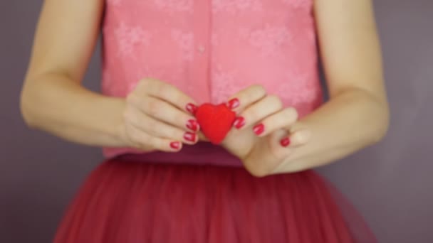 Little red heart in female hands, close up. Woman holds red heart gift for St. Valentine's Day. Concept of love. Female is showing red heart moves forward to camera — Stock Video