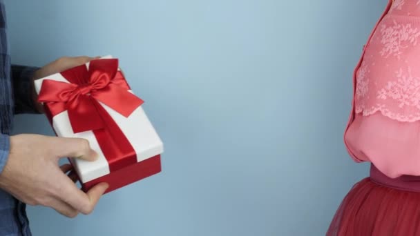 女性はバレンタインデーや誕生日にギフトボックスを受け取ります。男性の手は女性に赤いリボン弓と白いプレゼントボックスを与えています。お祝いのコンセプト — ストック動画