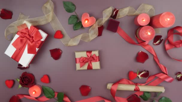 Festive background with rose petals, burning candles and gifts for St. Valentine's Day. Decorated table with red ribbons, roses flowers and red aroma candles. Concept of love and romance — Video Stock