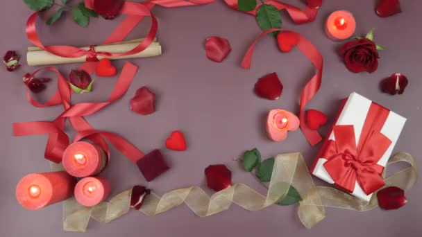 Burning red aroma candles, rose petals, red ribbon, gifts and little hearts are on table background. St. Valentine's day celebration. Concept of love and romance. Festive background — Stock videók