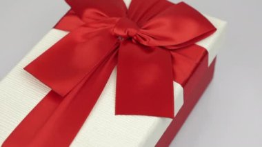 Sevgililer Günü sürprizi. Sevgililer günü hediyesi. Kırmızı kurdeleli beyaz hediye kutusu beyaz arka planda dönüyor. Romantik selamlaşma. Aşk ve romantizm kavramı