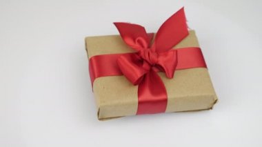 Kırmızı kurdeleli paketlenmiş hediye kutusu beyaz arka planda dönüyor. Sevgililer Günü hediyesi sürprizi. Sevgililer Günü ya da doğum günü için kırmızı kurdeleli hediye. Romantik selamlama