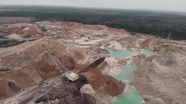 Gran cantera minera profunda con enormes montículos de minerales. La excavadora trabaja en la cantera minera. Equipo de minería en la arena o cantera de carbón. Industria minera. Cantera de arena, extracción de arena para la industria de la construcción — Vídeo de stock