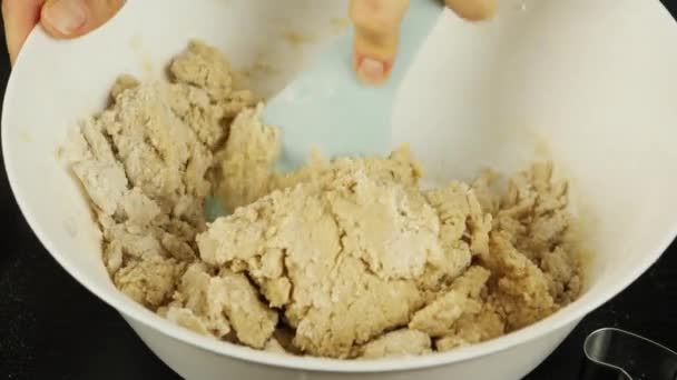 Proceso de amasar masa cruda para galletas de jengibre, cerrar. La mano femenina amasa la masa en un tazón utilizando paletas de cocina. Hacer galletas para el Día de San Valentín o Navidad. — Vídeos de Stock