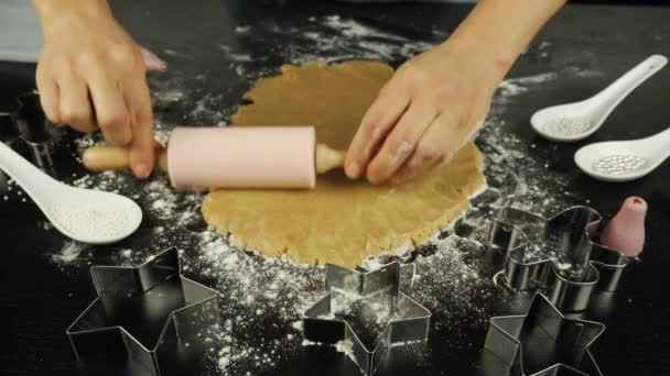 Händerna rullar rå deg med rullande stift på svart träbord i modernt kök. Kvinnlig kock lagar pepparkakor. Kvinna gör handgjorda kakor till St Valentine 's eller jul — Stockvideo