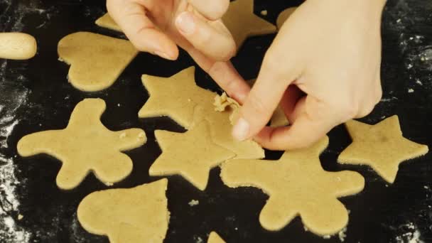 La mujer está haciendo galletas en forma de corazones, hombre de jengibre y estrellas. Las manos femeninas hacen galletas hechas a mano de masa cruda en la mesa en casa. Proceso de preparación de panadería — Vídeo de stock