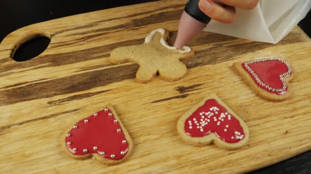 Décoration traditionnelle biscuit au pain d'épice pour Noël. Femme est vitrage bonbons festifs pour la Saint-Valentin. Biscuits et bonbons décorés sur table en bois. Processus de fabrication de biscuits au pain d'épice — Video