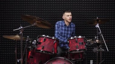 Müzisyen davulcu kayıt stüdyosunda davul setinde çalıyor.