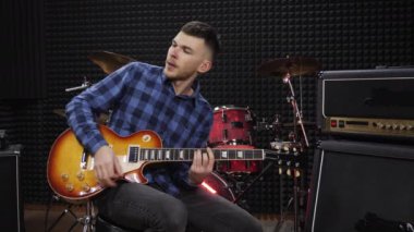 Müzisyen gitar telleriyle ses kayıt stüdyosunda gitar penası çalıyor.