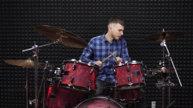 Müzisyen ses kayıt stüdyosunda davul setiyle çalıyor. Adam davul çalıyor.
