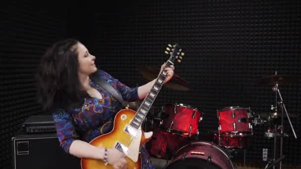 Woman is emotionally performing song on electric guitar at recording sound studio — Stock Video