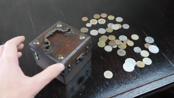 Рука відкриває стару коробку з антикварними монетами на коричневому фоні, крупним планом — стокове відео