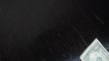 Masada bir Amerikan doları banknot var. El ahşap masaya 1 Amerikan doları koyar.