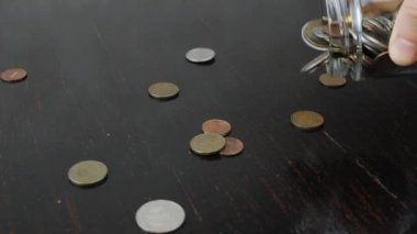 Eller cam para kutusundan madeni paralar döküyor.