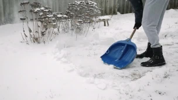 Az ember havat lapátol az udvaron hóviharban. Férfi takarítja hó közelében ház télen — Stock videók