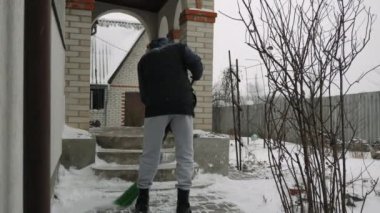 Adam kar fırtınasında merdivenlerden kar kürüyor.
