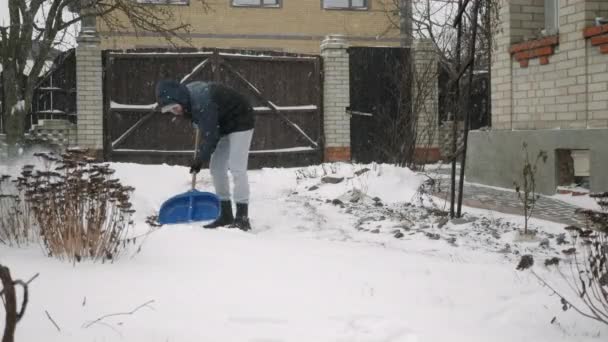 Snöfall. Unge man rensar stigen väg med spade från snö — Stockvideo