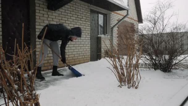 Man sopar snö från vägen på vintern. Människan skottar snö från stigen — Stockvideo