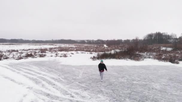 Молодая женщина катается на коньках по замерзшему озеру зимой — стоковое видео