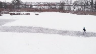 Kişi donmuş gölde buz pateni yapıyor. Derin çatlakları olan kalın bir buz tabakası.