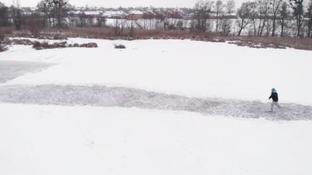 Человек катается на коньках по замёрзшему озеру с толстым льдом с глубокими трещинами — стоковое видео