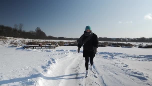 Молода жінка в чорній спідниці і білі фігурні ковзани це ковзани на замерзлому озері — стокове відео