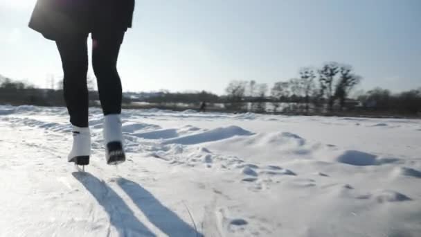 Woman is sliding along frozen ice on river. Female feet in white skates are skating — Stock Video