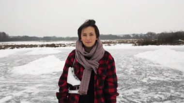 Dondurucu kış gününde donmuş gölde patenlerle duran genç bir kadının portresi.