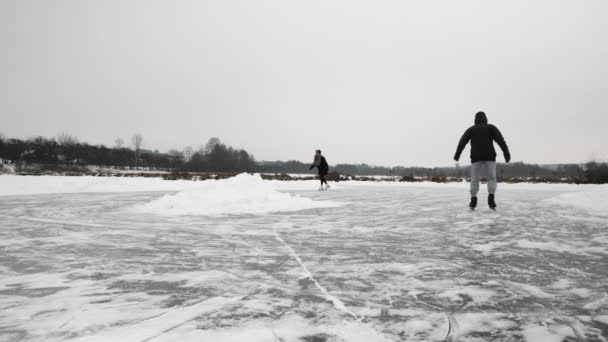 Mensen schaatsen buiten op bevroren meer. Vrienden schaatsen op kunstschaatsen — Stockvideo