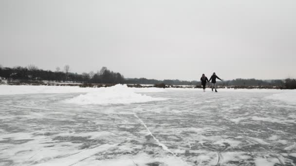 Amigos patinação no gelo ao ar livre no inverno. Casal romântico patina em patins no lago — Vídeo de Stock