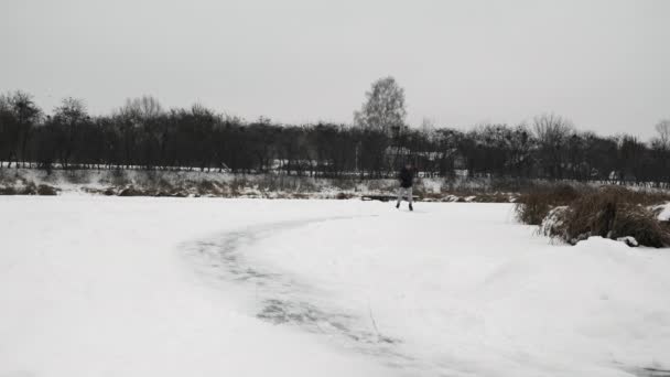 冬のアイススケート。黒いスケートの男が凍った湖で滑っている — ストック動画