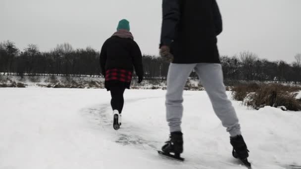 Mensen schaatsen op bevroren rivier. Vrienden in schaatsen glijden op dik ijs op het meer. — Stockvideo
