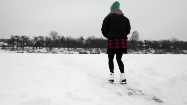 Woman is gliding on skates on thick ice on frozen lake. Female is ice skating — Stock Video