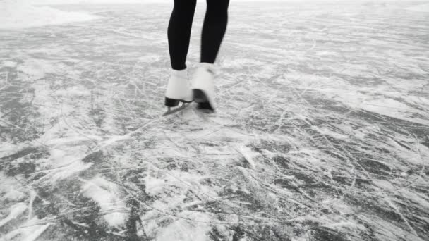 मादा टांगें जमे हुए झील पर आइस स्केटिंग करती हैं। स्केट्स में महिला मोटी बर्फ पर चढ़ रही है — स्टॉक वीडियो