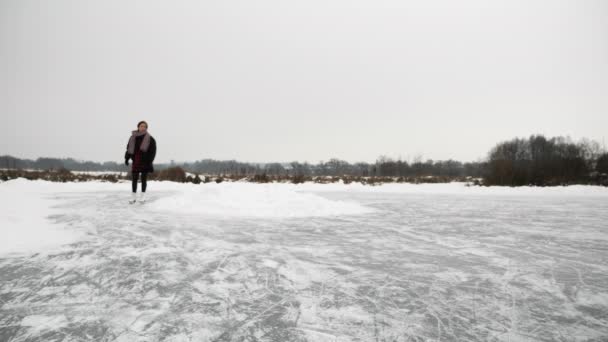 La mujer patina sobre hielo en el lago. Mujer en patines se desliza sobre hielo grueso congelado — Vídeos de Stock