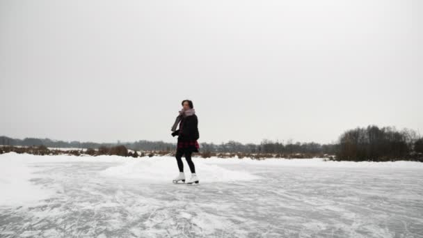 Weibchen laufen Schlittschuh auf zugefrorenem See. Eiskunstlauf im Winter — Stockvideo