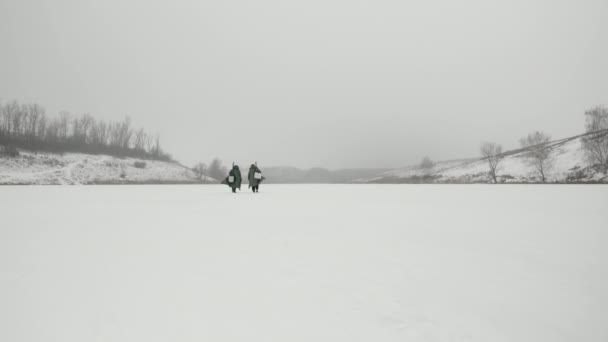 Οι ψαράδες με εξοπλισμό αλιείας είναι στην παγωμένη λίμνη. Οι άντρες ψαρεύουν το χειμώνα. — Αρχείο Βίντεο
