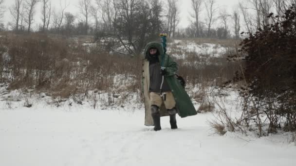 Pescatore con canna da pesca e trapano di ghiaccio è sul lago ghiacciato. Pesca invernale — Video Stock