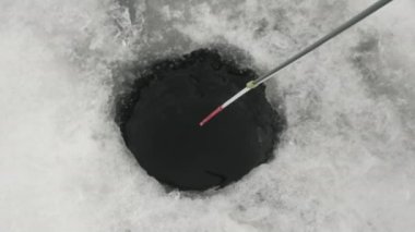 İnsan buz deliğinde balık yakalar. Kışın balık. Balıkçı donmuş nehirde balık tutuyor.