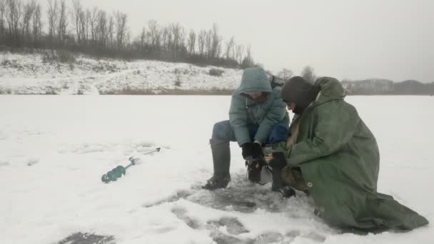 男たちは氷の穴で魚を捕っている。冬の釣り — ストック動画