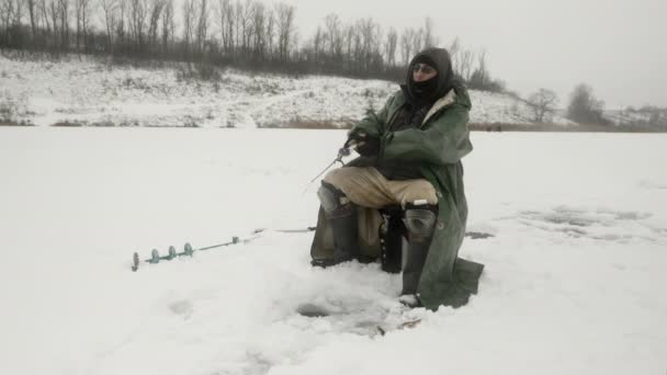 Concetto pesca invernale. Pescatore è la cattura di pesce in buco di ghiaccio — Video Stock