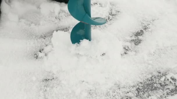 Buz matkabı buz deliği açıyor. Balıkçı buz deliği açıyor. Kış balıkçılık — Stok video